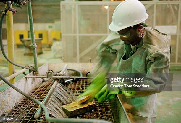 Mine worker scrubs and cleans a newly poured gold bar at Driefontein Gold Mine near Carltonville, South Africa. The mine is owned by Gold Fields Ltd....