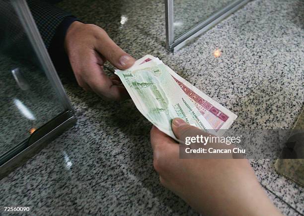 Passenger buys subway tickets with Chinese yuan banknotes at a ticket office on May 12, 2005 in Beijing, China. China's central bank said it will not...