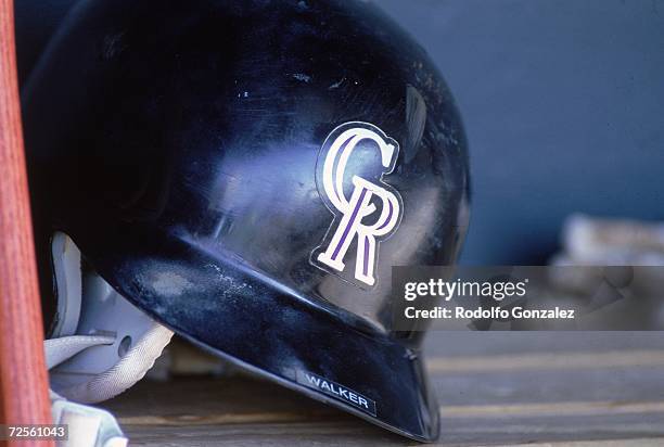 View a Colorado Rockies helmet on the dugout bench taken during a game against the St. Louis Cardinals at Coors Field in Denver, Colorado. The...