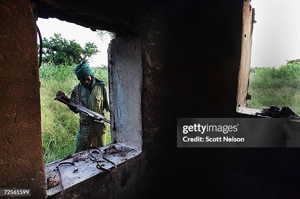 Sudanese rebel from the Justice and Equality Movement , investigates the scene in Ulang, a village recently burned by Janjaweed militiamen in the...