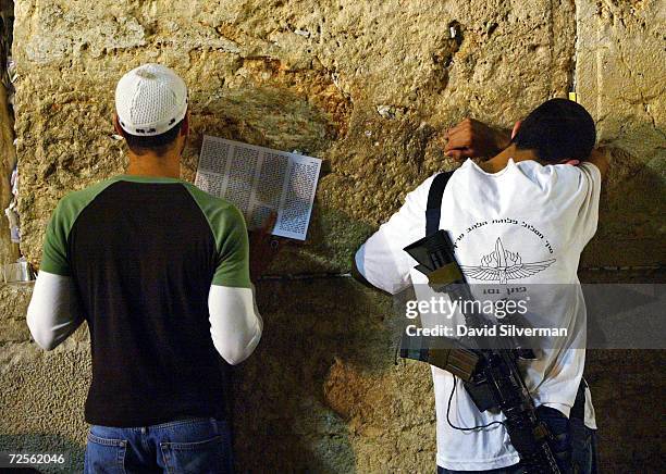 Religious Jews, one an Israeli soldier, pray before dawn at the Western Wall in Jerusalem's Old City during the annual 9th of Av memorial for the...