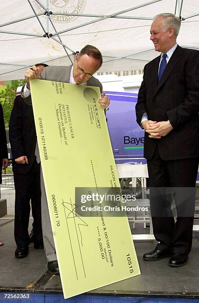 New York Mayor Rudolph Giuliani, left, looks over a donation check while New York City Comptroller Alan Hevesi laughs during a press conference June...