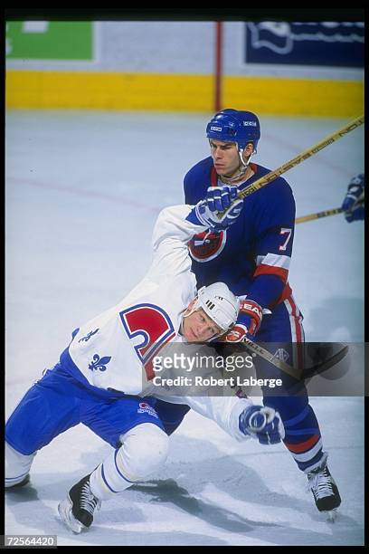 Defenseman Scott Lachance of the New York Islanders and defenseman Tommy Sjodin of the Quebec Nordiques tangle up during a game at the Quebec...