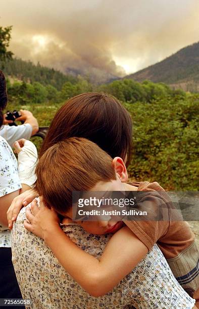 Five-year-old Caleb Aranzubia holds his mother Kari as she watches a fire in the Siskiyou National Forest August 2, 2002 in Kerby, Oregon. The...
