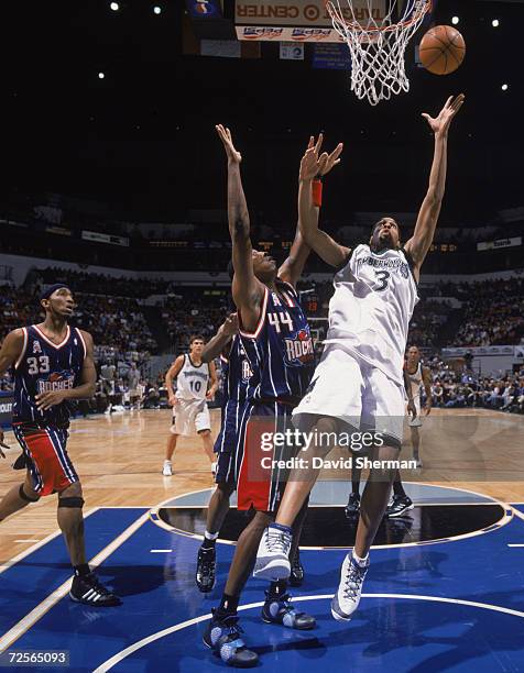 Loren Woods of the Minnesota Timberwolves jumps to make a basket as he is blocked Terence Morris of the Houston Rockets during the game at the Target...