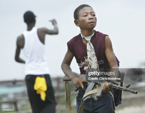 Child Liberian militia soldier loyal to the government walks away from firing while another taunts them on July 30, 2003 in Monrovia, Liberia....
