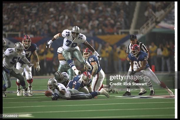 Defensive tackle Leon Lett of the Dallas Cowboys hurdles running back Thurman Thomas of the Buffalo Bills after Thomas fumbled the football during...