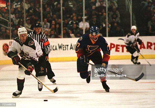 Defenseman Jim Johnson of the Phoenix Coyotes stick handles the puck as he burst up ice on a break away while being pursued by Joe Murphy of the St....