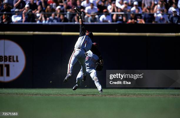 Barry Larkin of the Cincinnati Reds runs back to catch the ball as teammate Greg Vaughn backs him up during the game against the San Francisco Giants...