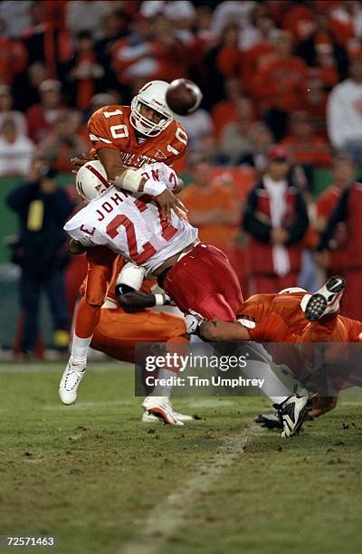 Quarterback Tony Lindsay of the Oklahoma State Cowboys throws the ball before being tackled by Eric Johnson of the Nebraska Cornhuskers during a game...