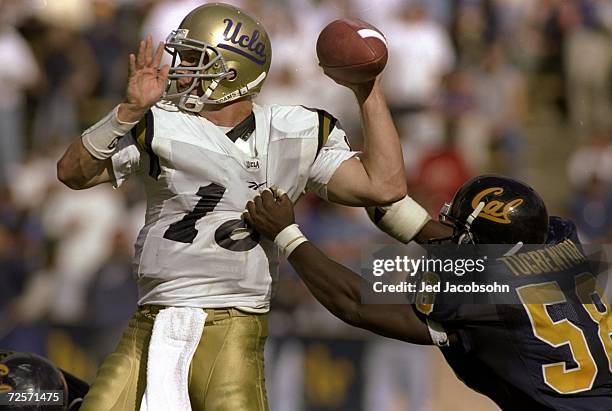 Quarterback Cade McNown of the UCLA Bruins is grabbed by Mawuko Tugbenyoh of the Cal Golden Bears during a game at the Memorial Stadium in Berkeley,...