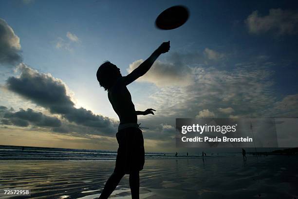 Balinese man plays frisbee as the sun sets on Kuta beach August 8, 2003 in Bali, Indonesia. Bali depends on tourism, which has picked up recently...