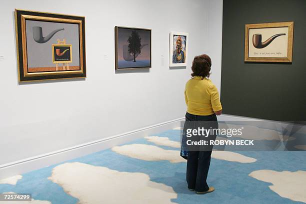 Los Angeles, UNITED STATES: A visitors views some of the most famous works by Belgian surrealist Rene Magritte including "Ceci N'est Pas Une Pipe" ,...