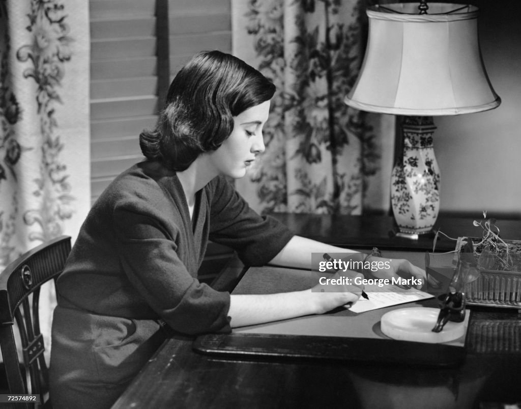Portrait of woman writing letter at desk