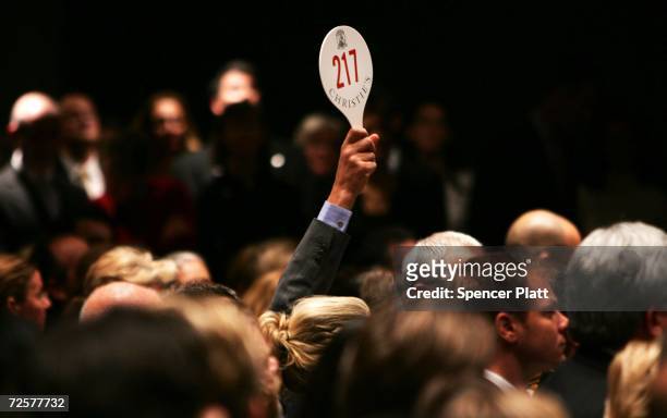 Man holds his hand up while bidding on a work of art inside the auction house Christie's during the Post-War and contemporary Art sale November 15,...