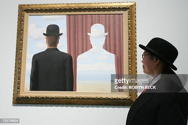 Los Angeles, UNITED STATES: Gallery security guard J. Dulay poses beside "Decalcomania" by Belgian surrealist artist Rene Magritte at the preview of...