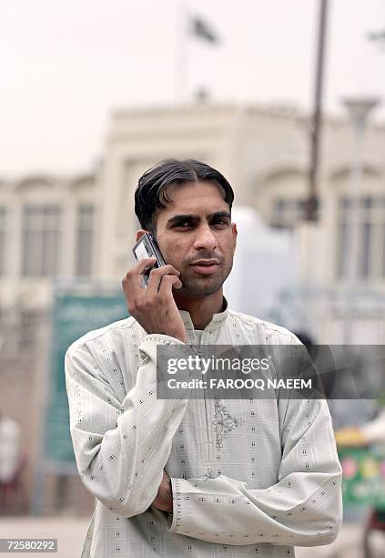 Saeed Hussain, cousin of jailed British national Mirza Tahir Hussain, talks on his cellphone as he waits outside the Adiala Jail to see Mirza in...