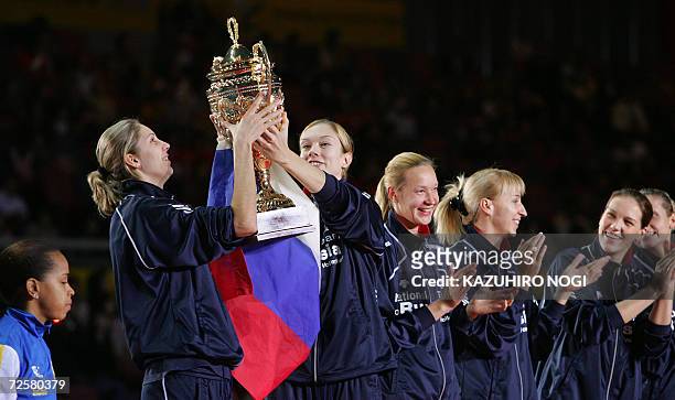 Russian volleyball players, Yulia Merkulova and Ekaterina Gamova hold the champion trophy while Brazilan team captain Helia Souza looks on during an...