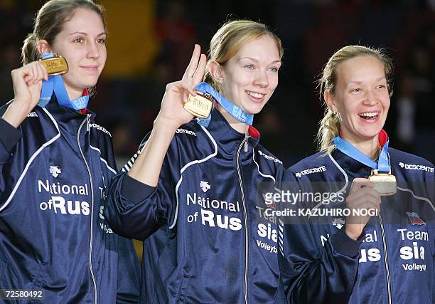 Russian volleyball team players, Yulia Merkulova , Ekaterina Gamova and Elena Godina , show their gold medals for photographers from the podium...
