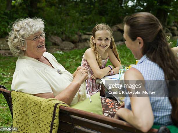 three female family members at garden table - old granny knitting stock-fotos und bilder