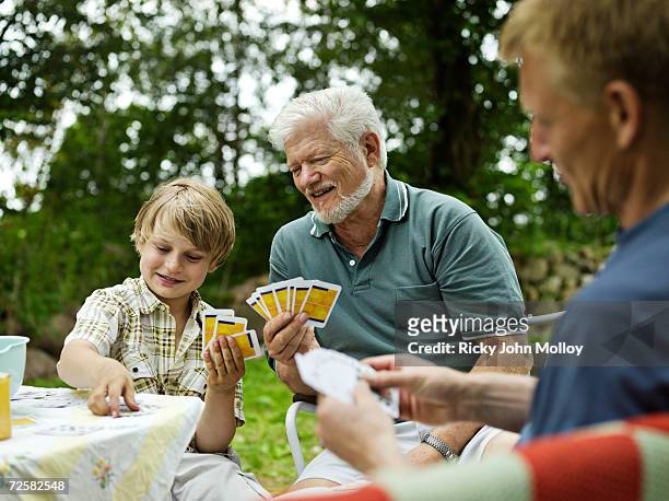 three male family members playing cards outdoors - generation gap stock pictures, royalty-free photos & images