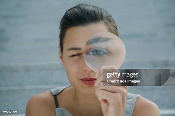 woman looking through magnifying glass - lens eye stock pictures, royalty-free photos & images