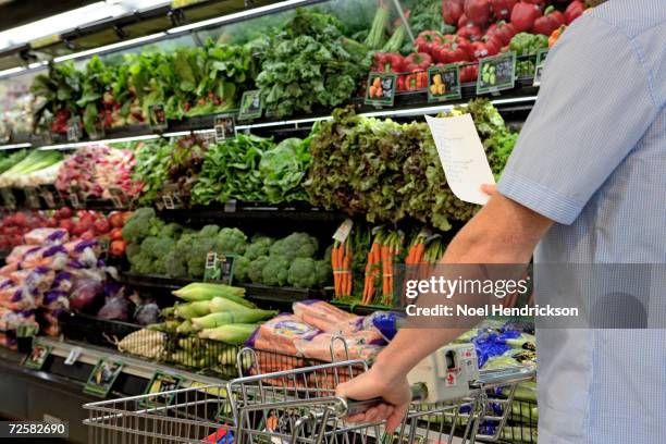 man with shopping list in supermarket, mid section - lista della spesa foto e immagini stock