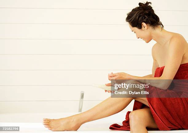 woman wrapped in towel, holding bottle of bath salts - badzout stockfoto's en -beelden