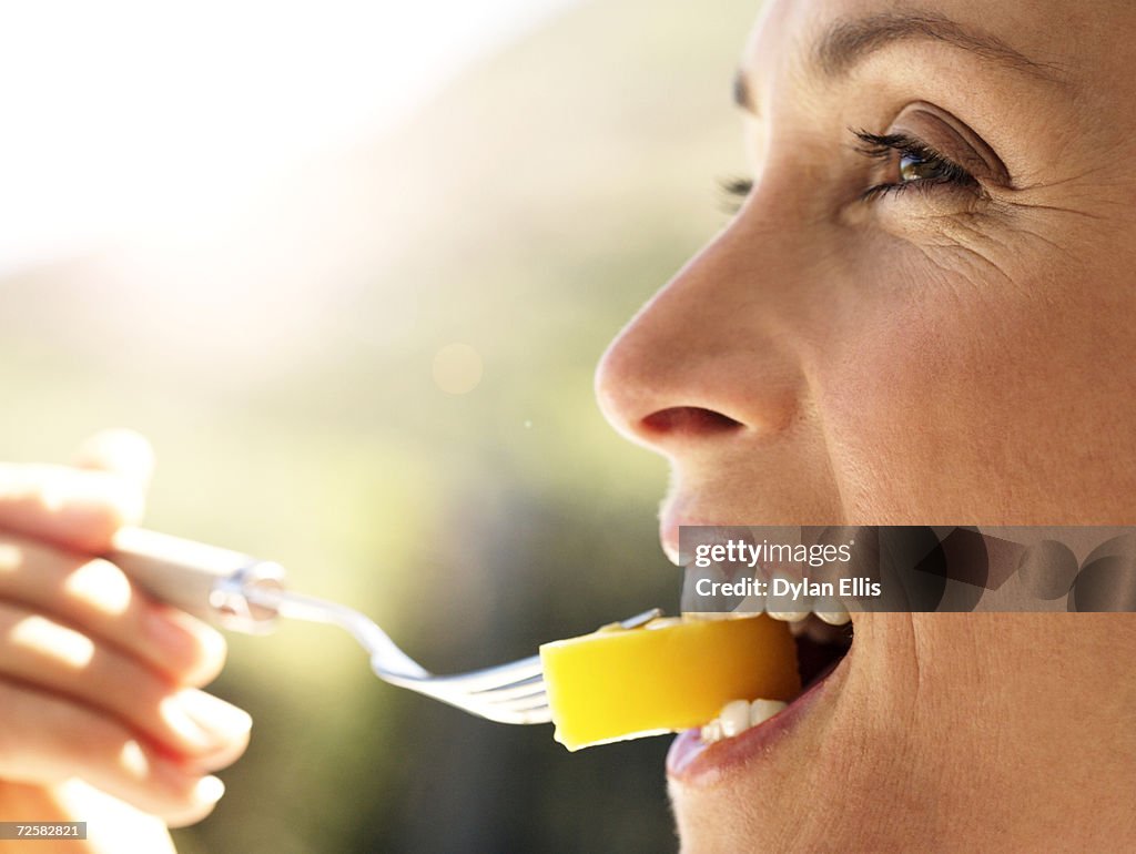 Woman eating fruit salad, smiling, side view
