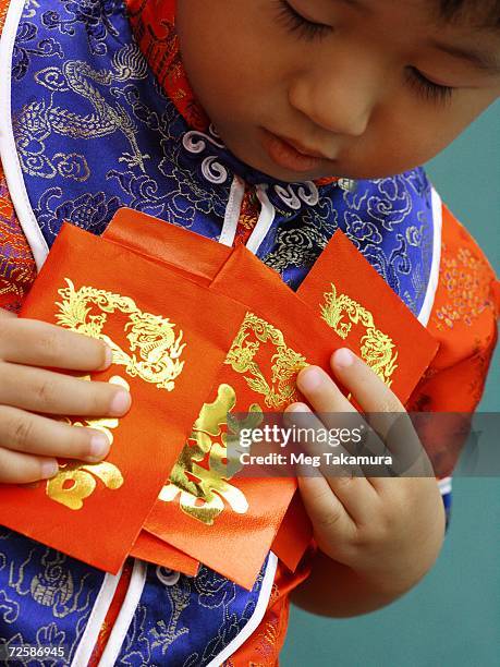 close-up of a boy holding red gift packets (hong bao) - chinese new year red envelope stock pictures, royalty-free photos & images