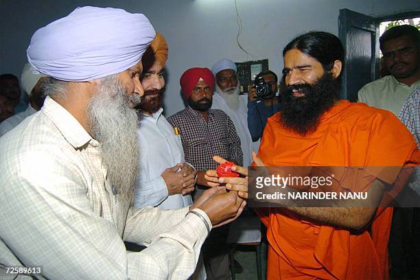 An Indian prisoner presents a flower to Yoga Guru Swami Ramdev as he arrives at The Central Jail in Amritsar,17 November 2006. Hundreds of prisoners...