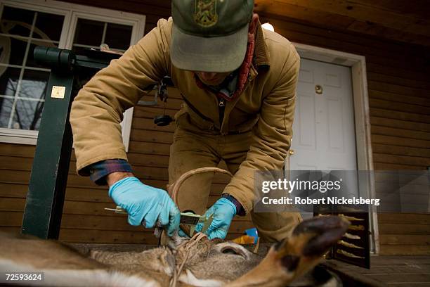 Vermont state wildlife biologist notes the data from a recently shot whitetail deer as the hunter, Perle Webb, Sr., not shown, looks on November 12,...