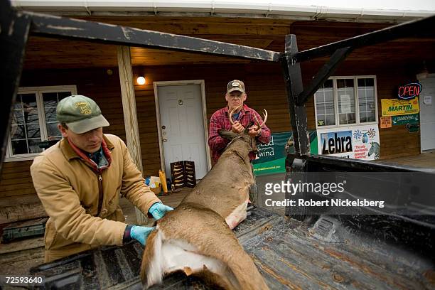 Vermont state wildlife biologist, left, loads a deer after noting the data from a recently shot whitetail deer as the hunter, Perle Webb, Sr.,...