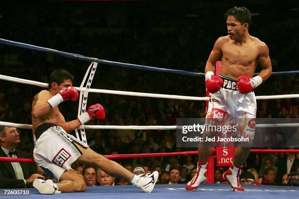 Manny Pacquiao of the Philippines watches as Erik Morales of Mexico is knocked down during the second round during their super featherweight bout at...