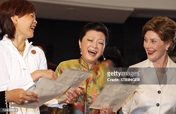 Akie Abe from Japan, Mrs. Chang from Taiwan and US First Lady Laura Bush react while looking at Vietnamese traditional woodblock prints during a...