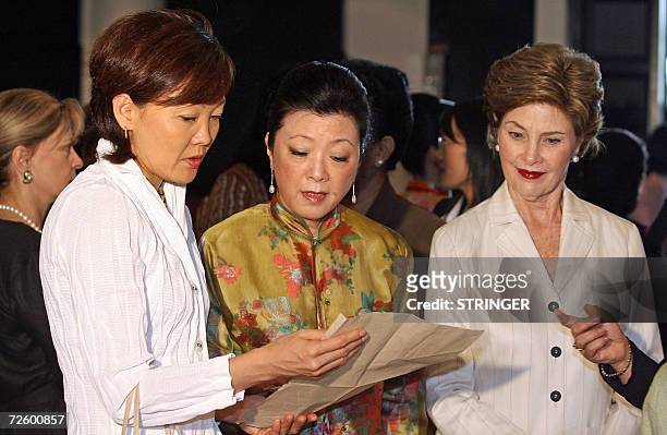 Akie Abe from Japan, Mrs. Chang from Taiwan and US First Lady Laura Bush discuss Vietnamese traditional woodblock prints during a visit by spouses of...