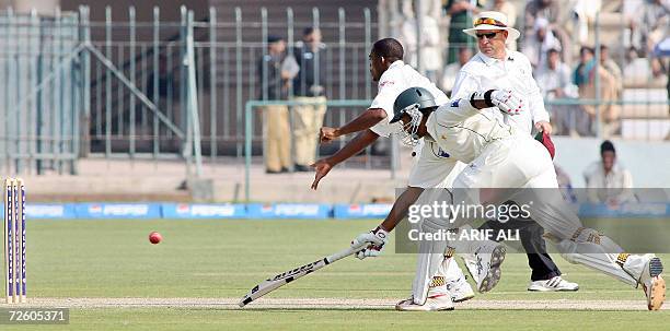 Pakistani cricketer Danish Kaneria makes an unsuccessful attempt to avoid a run out by West Indies cricketer, Daren Powell during the second day of...