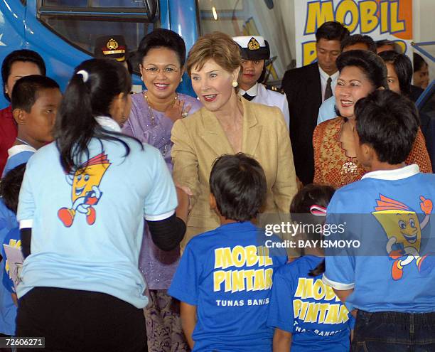 First Lady Laura Bush stands next to Indonesia's First Lady Ani Yudhoyono while inspecting an educational material for mothers, children and local...