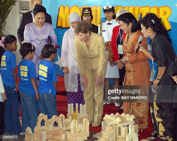 First Lady Laura Bush stands next to Indonesia's First Lady Ani Yudhoyono while inspecting educational material for mothers, children and local...