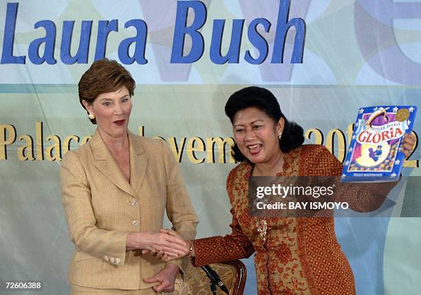 First Lady Laura Bush hands over a book to Indonesia's First Lady Ani Yudhoyono to symbolize her donation of thousands of books for the children...
