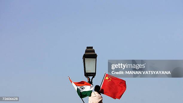 An Indian worker ties a Chinese national flag on an electricity pole near the India Gate, in New Delhi, 20 November 2006, hours ahead of the visit by...