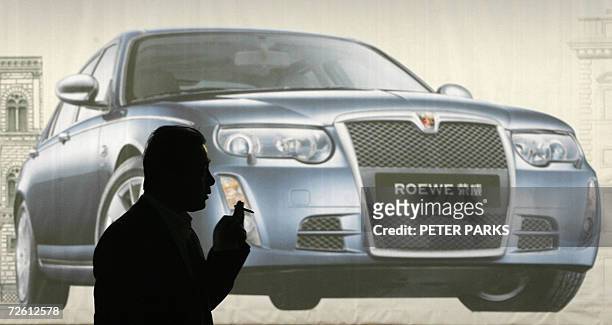 Man passes infront of an advertisement for the Chinese-made Roewe 750 car at Beijing's Capital airport 21 November 2006. The luxury model car is made...