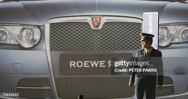 Parking attendant waits for cars in front of an advertisement for the Chinese-made Roewe 750 car at Beijing's Capital airport 21 November 2006. The...