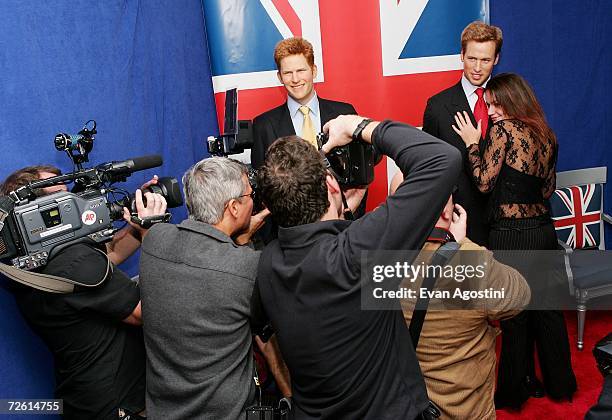 Photographers take pictures of fan Pamela Fry from Long Island, NY posing with statues of British Royals Prince William and Prince Harry during a wax...