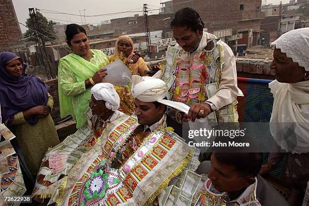 Positive father Nazir Masih places a ceremonial Punjabi turban onto the head of his son Samuel at the son's wedding on November 11, 2006 in Lahore,...