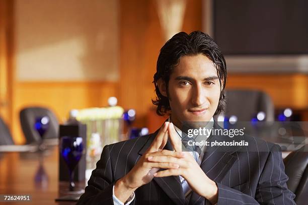 portrait of a businessman sitting in a conference room and smiling - etnia indo asiatica fotografías e imágenes de stock