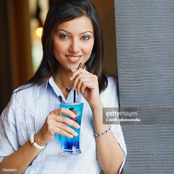 portrait of a young woman holding a glass of cocktail - rietje los stockfoto's en -beelden