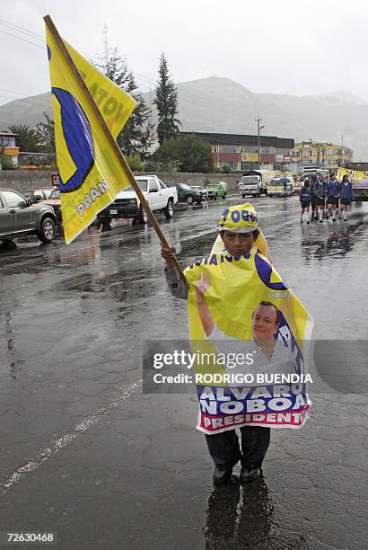 Un nino se cubre de la lluvia con afiches del candidato presidencial Alvaro Noboa en el sur de Quito el 22 de noviemre de 2006, antes del inicio del...