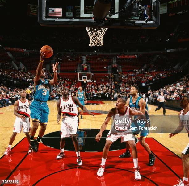 Chris Paul of the New Orleans/Oklahoma City Hornets drives to the basket for a layup past Zach Randolph and Jamaal Magloire of the Portland Trail...