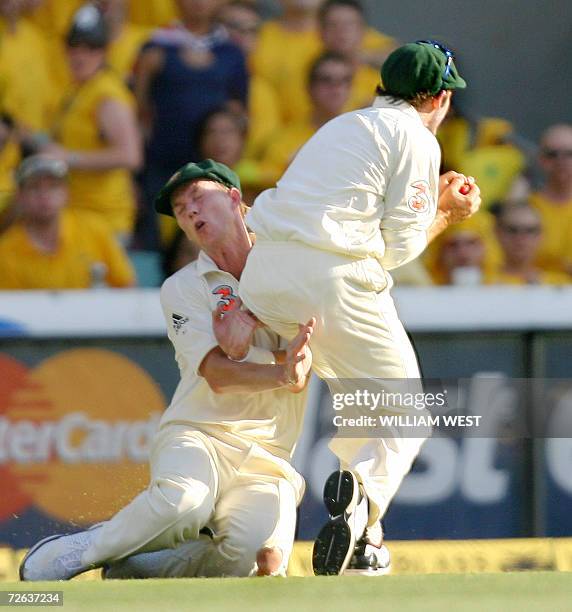 Australian fieldsman Mike Hussey catches England batsman Andrew Strauss but injures fellow fieldsman Brett Lee' knee on the second day of the first...